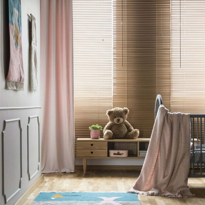 Pink blanket on bed and rug in bright baby's room interior with